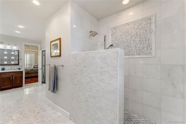 bathroom featuring tile walls, tiled shower, and vanity