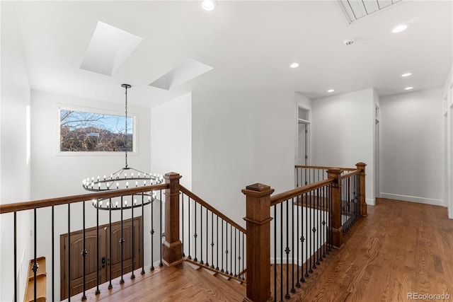 corridor featuring a skylight, an inviting chandelier, and hardwood / wood-style flooring