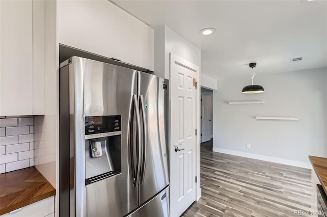 4932 Jasper St, Denver, CO 80239 - kitchen featuring stainless steel refrigerator with ice dispenser, wood finished floors, white cabinetry, hanging light fixtures, and wooden counters