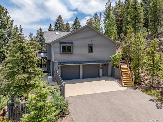 6882 Snowshoe Trl, Evergreen, CO 80439 - view of front of property featuring stairs, an attached garage, driveway, and roof with shingles