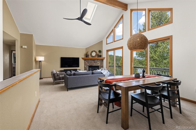 6882 Snowshoe Trl, Evergreen, CO 80439 - dining room featuring light colored carpet, high vaulted ceiling, a ceiling fan, beamed ceiling, and a stone fireplace