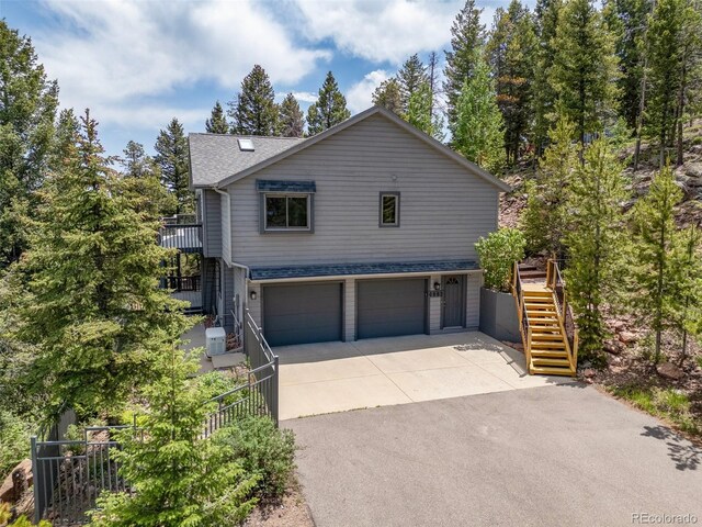 6882 Snowshoe Trl, Evergreen, CO 80439 - view of front of property with stairs, an attached garage, asphalt driveway, and a shingled roof