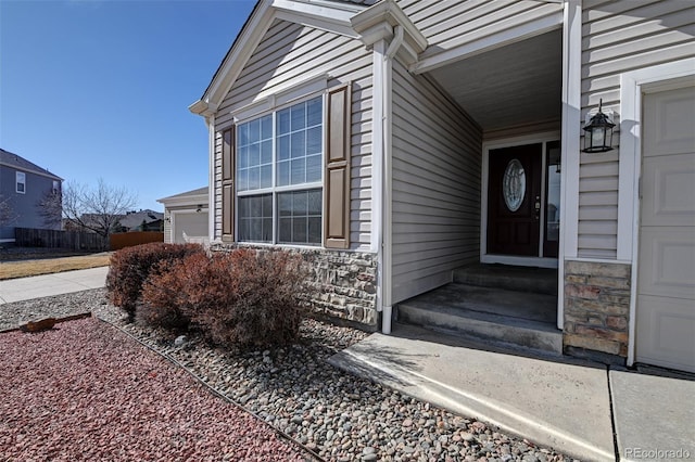 doorway to property featuring a garage and stone siding