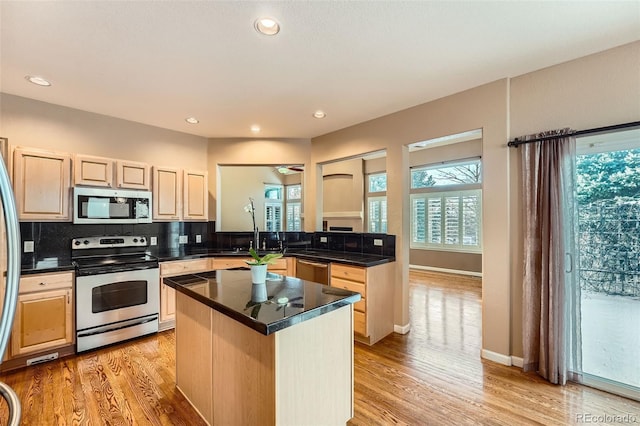 kitchen with tasteful backsplash, a center island, kitchen peninsula, stainless steel appliances, and light wood-type flooring