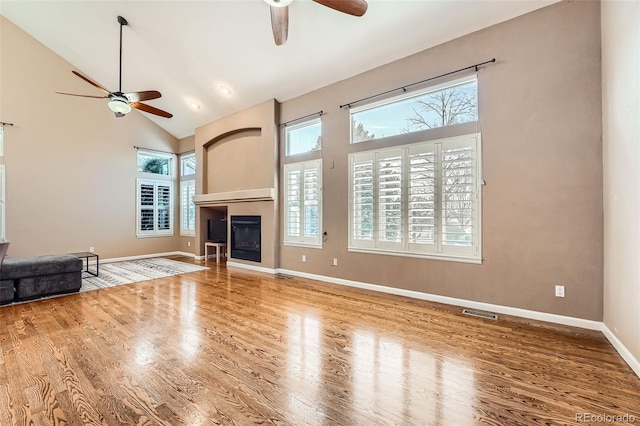 unfurnished living room featuring hardwood / wood-style flooring, ceiling fan, and high vaulted ceiling