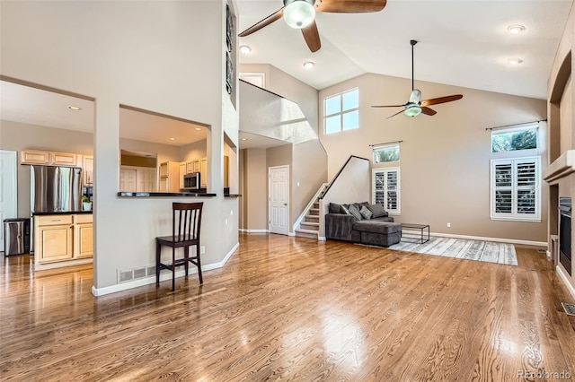 living room with hardwood / wood-style flooring, ceiling fan, and high vaulted ceiling