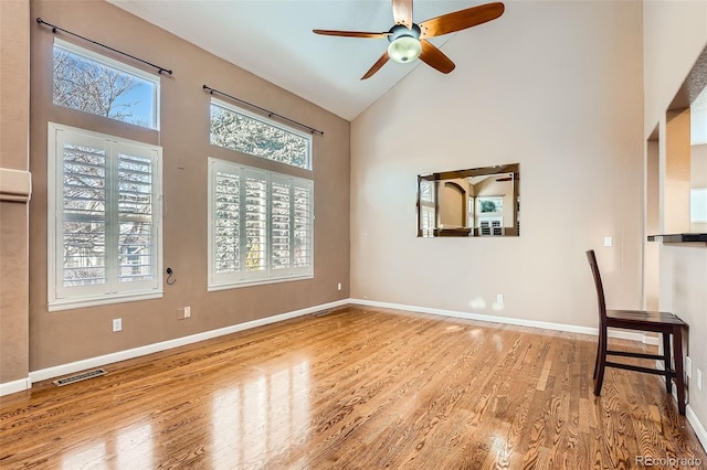 empty room featuring ceiling fan, light wood-type flooring, and high vaulted ceiling