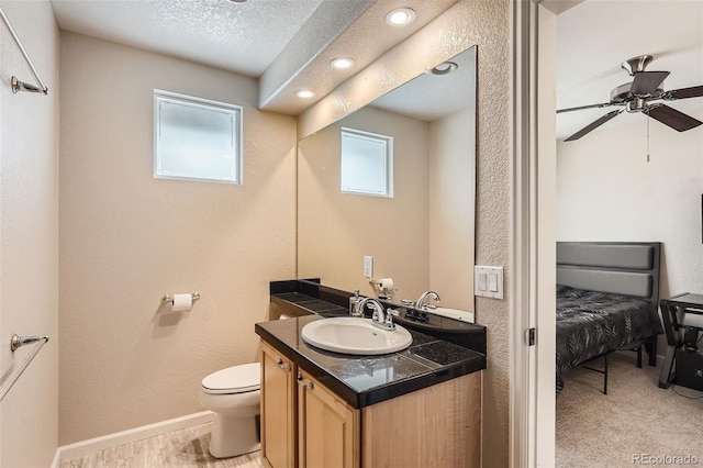 bathroom with ceiling fan, vanity, toilet, and a textured ceiling