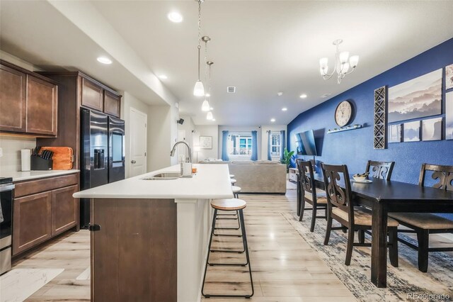 4026 Tiberias Pt, Colorado Springs, CO 80916 - kitchen with black refrigerator with ice dispenser, sink, a center island with sink, a chandelier, and hanging light fixtures