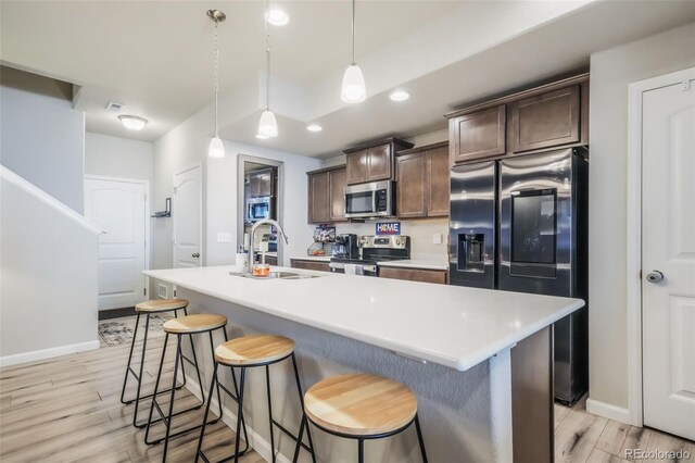 4026 Tiberias Pt, Colorado Springs, CO 80916 - kitchen with dark brown cabinetry, stainless steel appliances, a kitchen island with sink, sink, and hanging light fixtures
