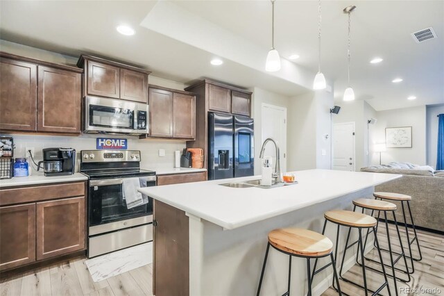 4026 Tiberias Pt, Colorado Springs, CO 80916 - kitchen featuring pendant lighting, a breakfast bar, a center island with sink, sink, and stainless steel appliances