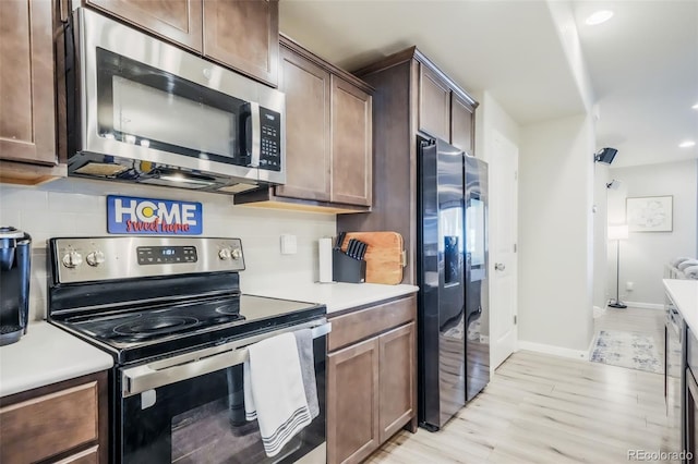 4026 Tiberias Pt, Colorado Springs, CO 80916 - kitchen featuring appliances with stainless steel finishes, light wood-type flooring, tasteful backsplash, and dark brown cabinets