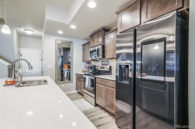 4026 Tiberias Pt, Colorado Springs, CO 80916 - kitchen with dark brown cabinetry, sink, light hardwood / wood-style floors, pendant lighting, and appliances with stainless steel finishes