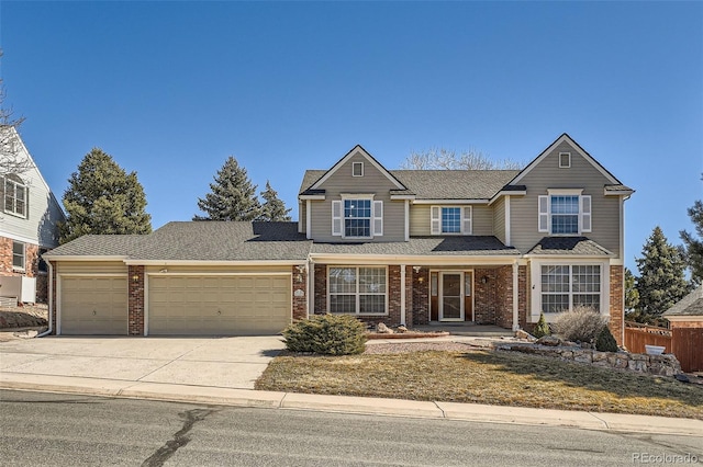 traditional-style home featuring an attached garage, driveway, fence, and brick siding