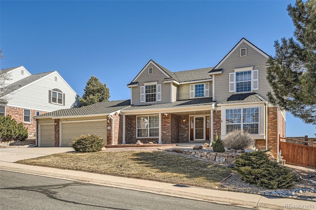 traditional-style home featuring an attached garage, fence, concrete driveway, and brick siding