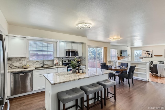 kitchen with dark wood-style flooring, a breakfast bar area, tasteful backsplash, appliances with stainless steel finishes, and a sink