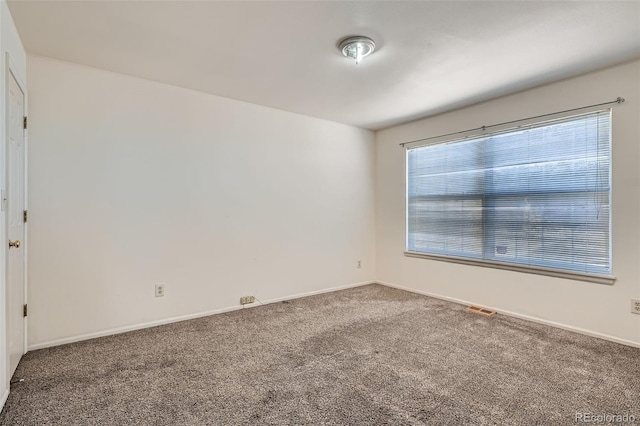 empty room featuring carpet floors, visible vents, and baseboards