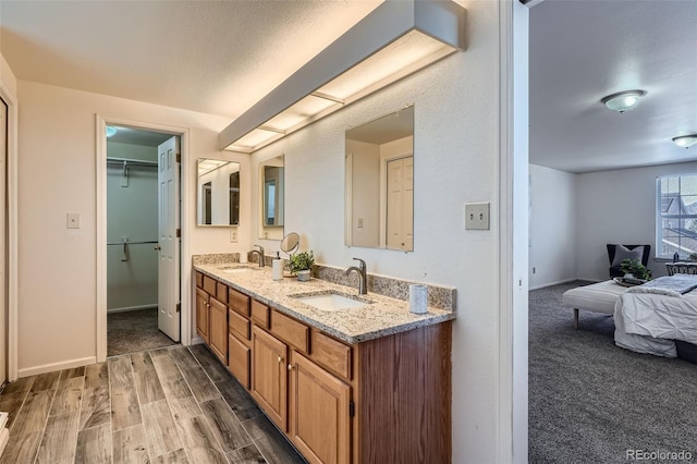 full bathroom featuring double vanity, a sink, baseboards, and wood finished floors