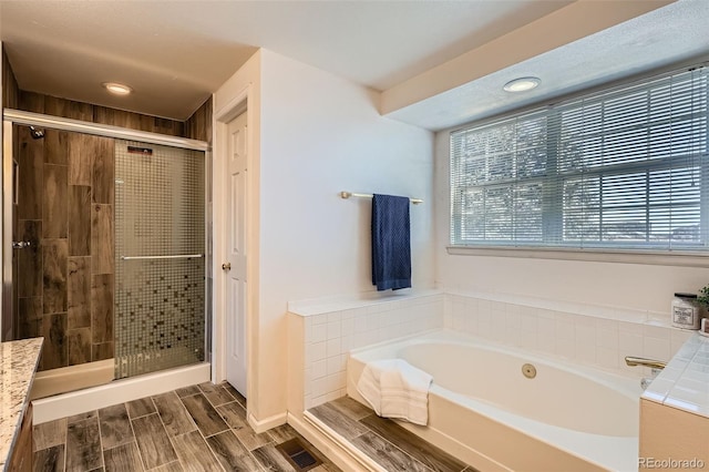 full bathroom featuring a stall shower, a bath, and wood tiled floor