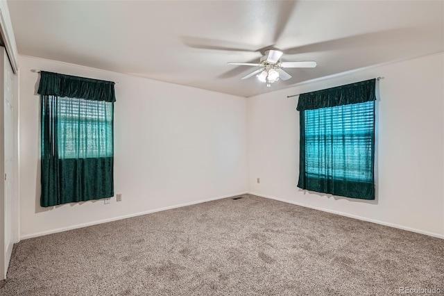 carpeted spare room with ceiling fan and baseboards