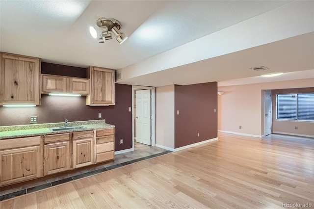 kitchen featuring light brown cabinets, light wood-style flooring, a sink, and visible vents