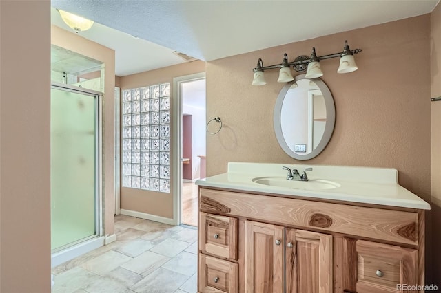 full bathroom with a stall shower, visible vents, a textured wall, and vanity