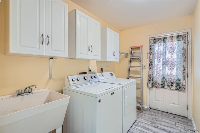 laundry room with cabinet space, light wood-style floors, a sink, and washing machine and clothes dryer