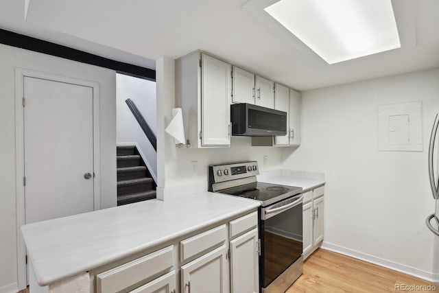 kitchen with stainless steel appliances, light wood-type flooring, light countertops, white cabinetry, and baseboards