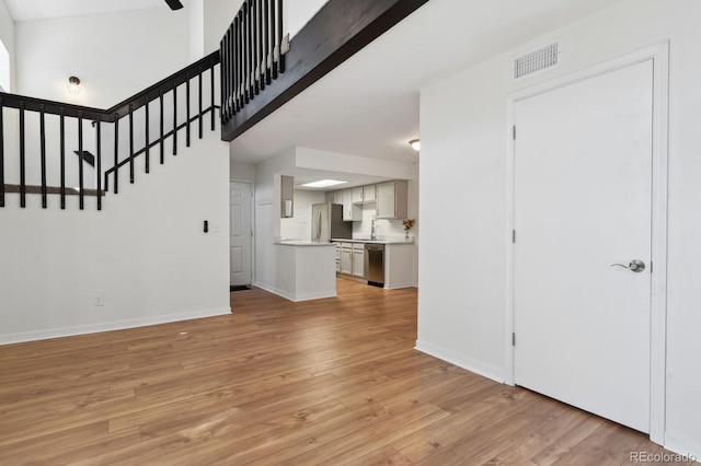 unfurnished living room with light wood-type flooring, baseboards, and a sink