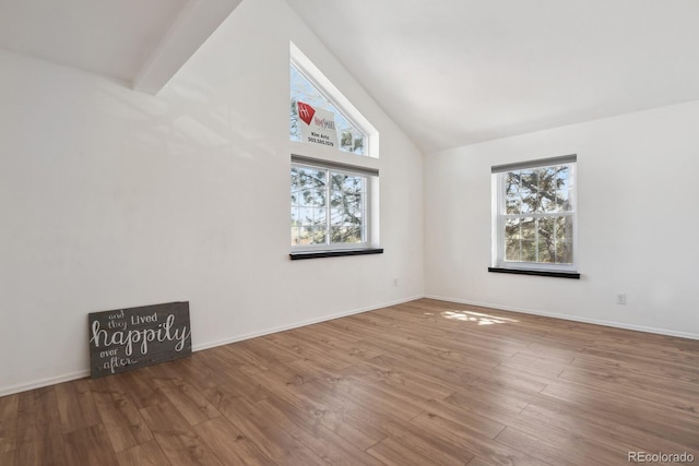 bonus room with plenty of natural light, wood finished floors, high vaulted ceiling, and baseboards