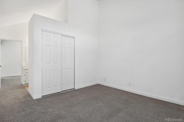 unfurnished bedroom with carpet flooring, baseboards, a closet, and vaulted ceiling