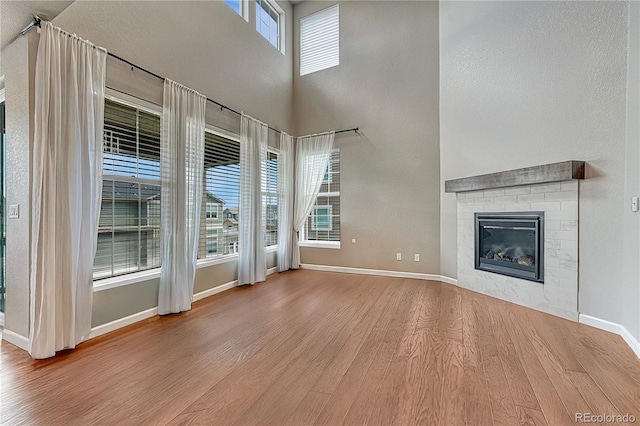 23957 E Rocky Top Ave, Aurora, CO 80016 - unfurnished living room with wood finished floors, a fireplace, and a towering ceiling