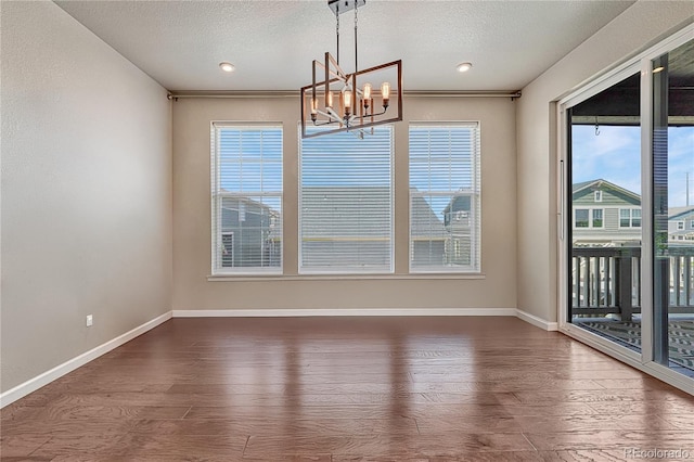 23957 E Rocky Top Ave, Aurora, CO 80016 - unfurnished dining area featuring a chandelier, wood finished floors, and a textured ceiling