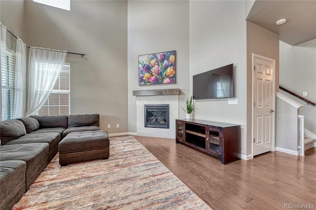 23957 E Rocky Top Ave, Aurora, CO 80016 - living area featuring wood finished floors, a glass covered fireplace, stairs, and a towering ceiling