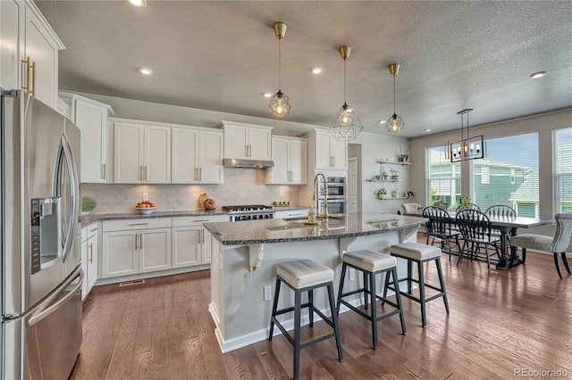 23957 E Rocky Top Ave, Aurora, CO 80016 - kitchen featuring stainless steel fridge, under cabinet range hood, stove, white cabinetry, and recessed lighting