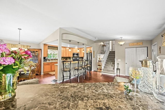 12625 W 66th Cir, Arvada, CO 80004 - kitchen featuring lofted ceiling, dark wood finished floors, stainless steel appliances, a breakfast bar, and a center island
