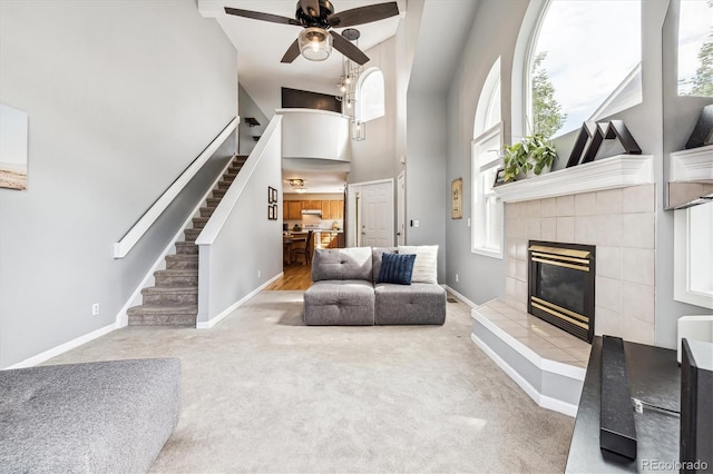 living room with a towering ceiling, carpet floors, ceiling fan, and a fireplace