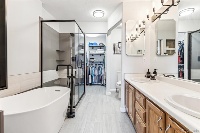 full bathroom with independent shower and bath, a textured ceiling, vanity, and toilet