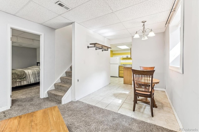 carpeted dining area featuring a paneled ceiling and an inviting chandelier