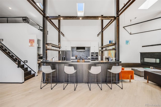 2801 Lawrence St, Denver, CO 80205 - kitchen with a towering ceiling, stainless steel fridge, a skylight, white cabinets, and a kitchen bar
