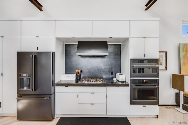 2801 Lawrence St, Denver, CO 80205 - kitchen with high end refrigerator, wall chimney exhaust hood, dark countertops, white cabinetry, and stainless steel gas stovetop