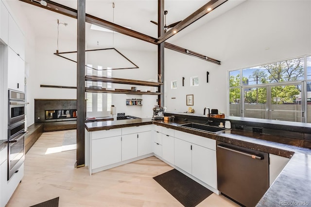 2801 Lawrence St, Denver, CO 80205 - kitchen with stainless steel appliances, high vaulted ceiling, a sink, dark countertops, and white cabinets