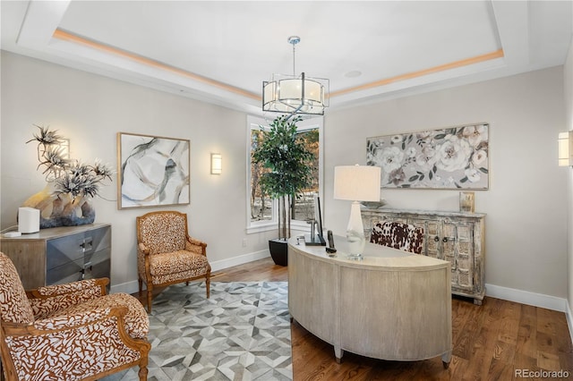 office with wood-type flooring, a notable chandelier, and a tray ceiling