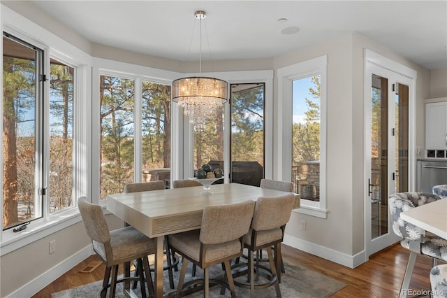 dining space with a notable chandelier, hardwood / wood-style flooring, a wealth of natural light, and french doors