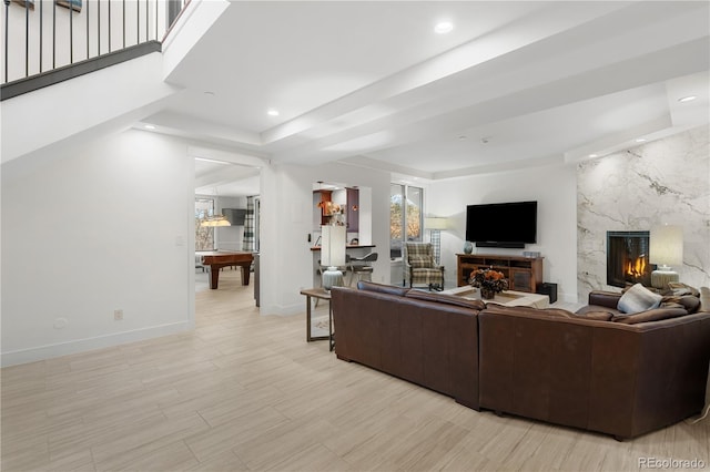 living room with a raised ceiling, a fireplace, and light hardwood / wood-style floors