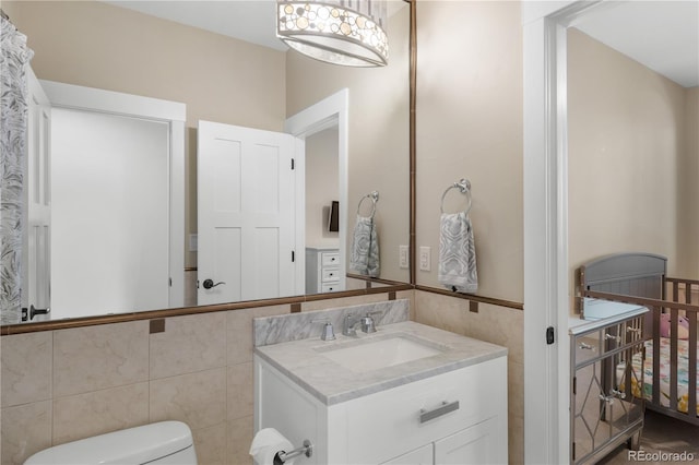 bathroom with vanity, tile walls, and toilet