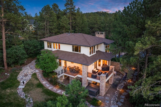 back house at dusk with a patio and an outdoor living space with a fireplace