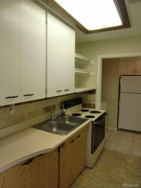 kitchen with tasteful backsplash, sink, white appliances, and white cabinetry