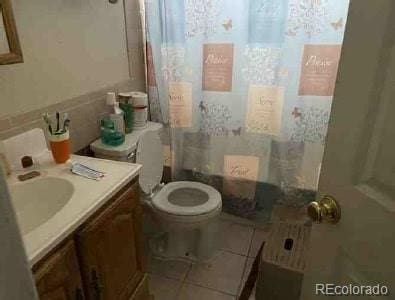 bathroom with vanity, curtained shower, tile patterned floors, and toilet