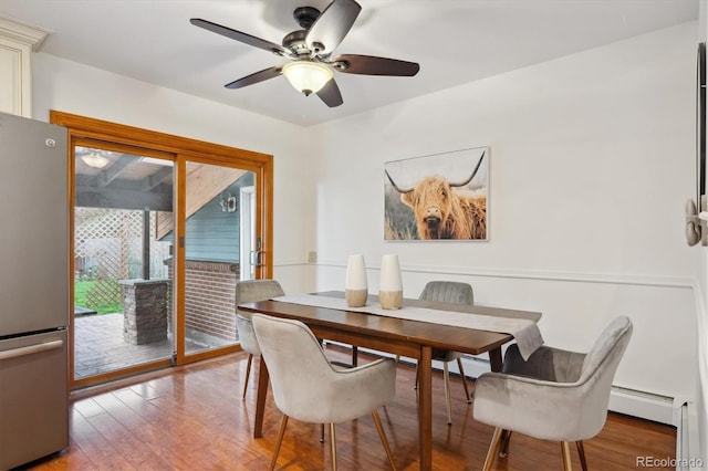 dining space with a ceiling fan, wood finished floors, and a baseboard radiator